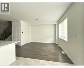 A spacious room with wooden flooring and a staircase on the left side.