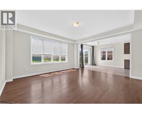 A spacious room with wooden flooring and a large window with blinds.