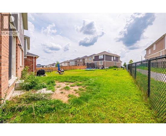 A grassy area in front of a row of houses with a fence on the right side.