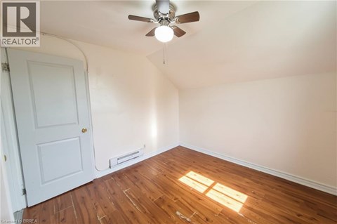 A room with a ceiling fan and a window letting in sunlight.
