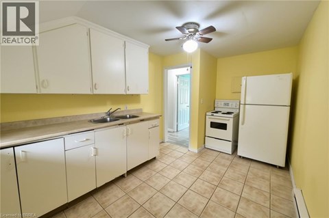 A kitchen with white cabinets and a white fridge.