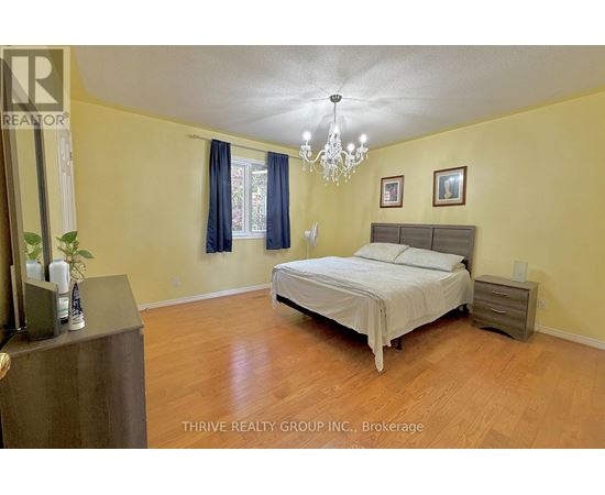 A bedroom with a bed, nightstand, and a chandelier.