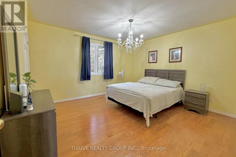A bedroom with a bed, nightstand, and a chandelier.