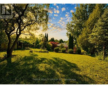 A lush green lawn with trees and a house in the background.