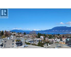 A cityscape with buildings and a mountain in the background.