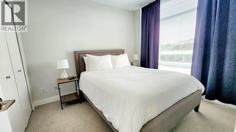 A bedroom with a large bed and a window with curtains.