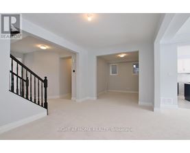 A spacious room with a staircase on the left and a door on the right.