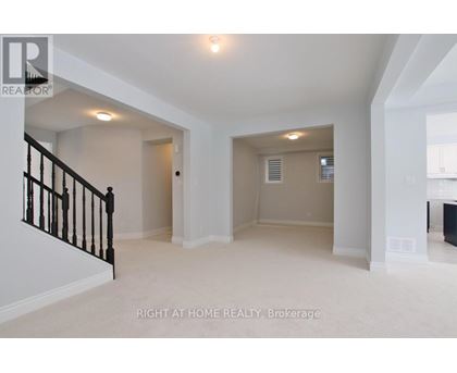 A spacious room with a staircase on the left and a door on the right.