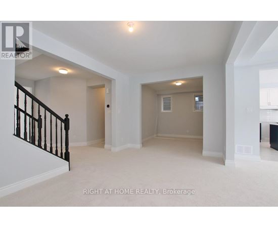 A spacious room with a staircase on the left and a door on the right.