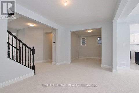 A spacious room with a staircase on the left and a door on the right.