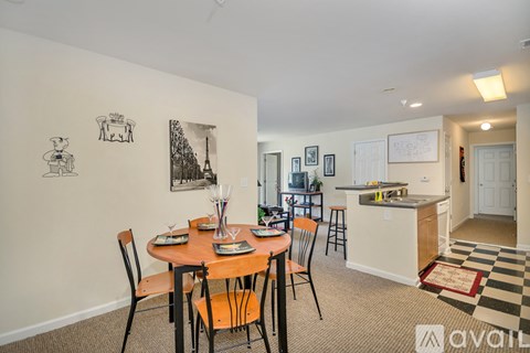A dining room with a table set for six with a view of the kitchen.