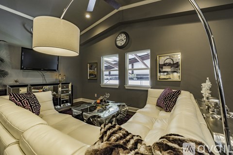 A living room with a white couch and a flat screen TV mounted on the wall.