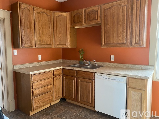 A kitchen with wooden cabinets and a white dishwasher.