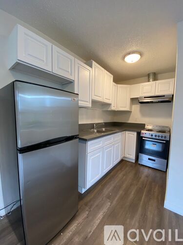 A kitchen with a stainless steel refrigerator and white cabinets.