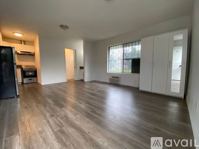 A spacious room with wooden flooring and white walls.