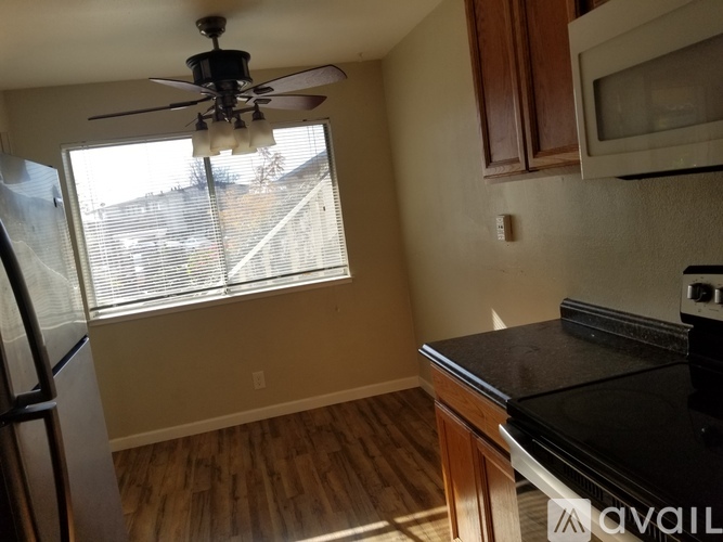 A kitchen with a black countertop and a ceiling fan.