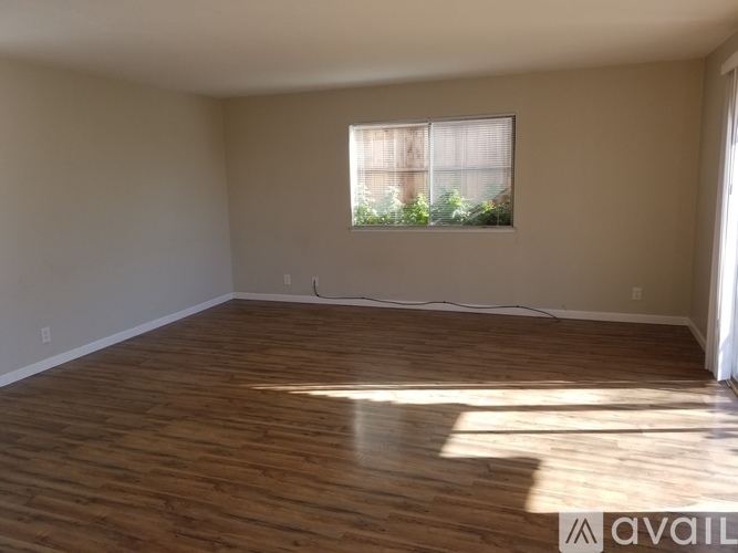 Empty room with wooden flooring and a window.
