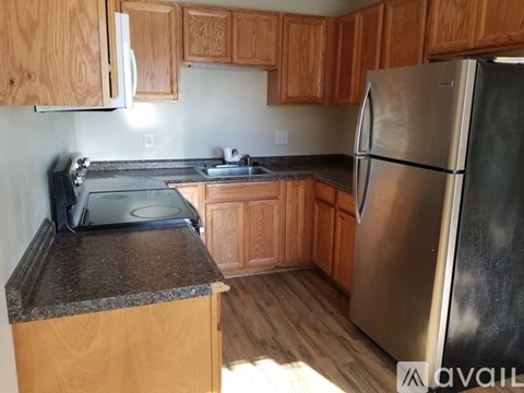 A kitchen with wooden cabinets and a stainless steel refrigerator.
