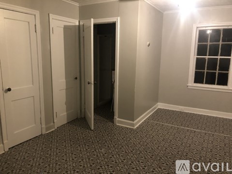 A room with a carpeted floor, a window, and a door.