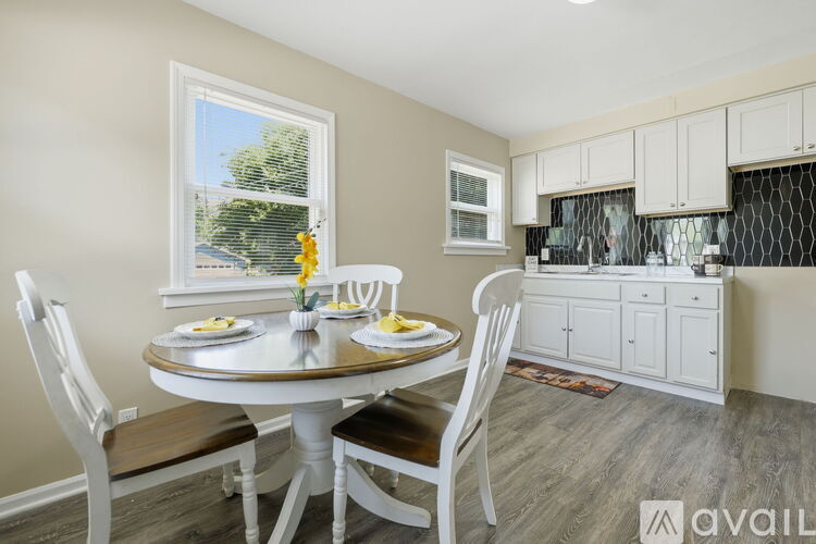 A dining room with a table set for two and a kitchen area in the background.