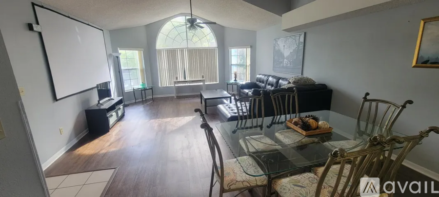 A living room with a black couch and a glass table.