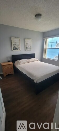 A bedroom with a bed, nightstand, and two pictures on the wall.