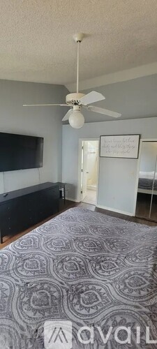 A bedroom with a bed and a ceiling fan.