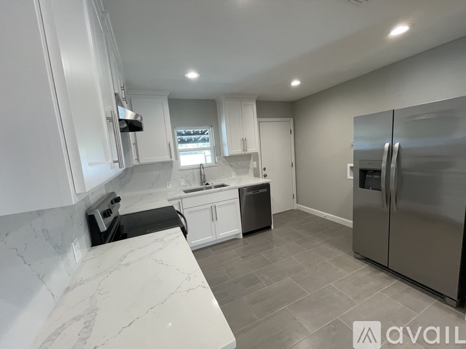 A kitchen with white cabinets and a marble countertop.