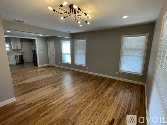 A spacious room with wooden flooring and a chandelier.