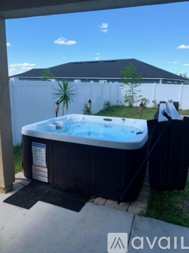 A hot tub is sitting on a patio with a black mat in front of it.