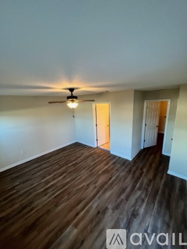 A room with wooden flooring and a ceiling fan.