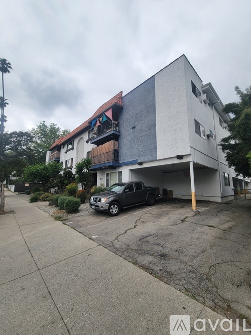 A grey Nissan truck is parked in front of a two-story building.