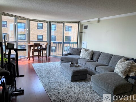A living room with a grey couch and a treadmill.
