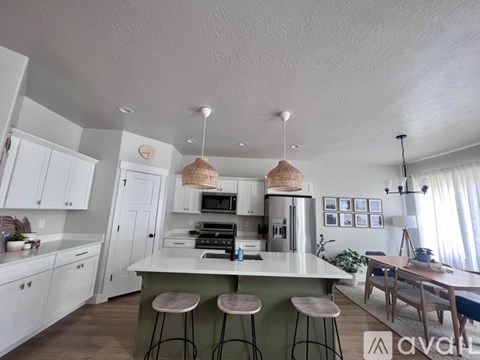 A kitchen with white cabinets and a green island.