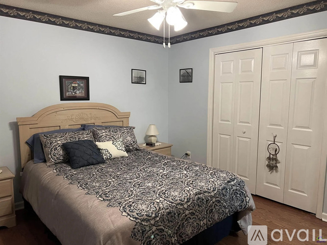 A bedroom with a bed, a ceiling fan, and two doors.