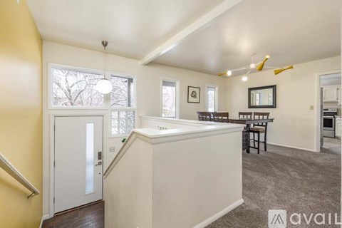 A living room with a white door and a dining table with chairs.