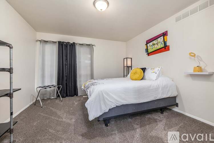 A bedroom with a bed, a chair, and a painting on the wall.