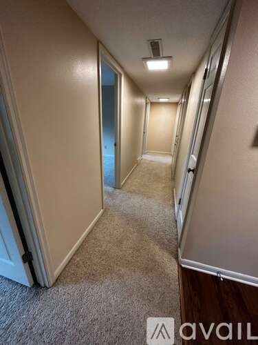 A long hallway with carpeted floors and white walls.