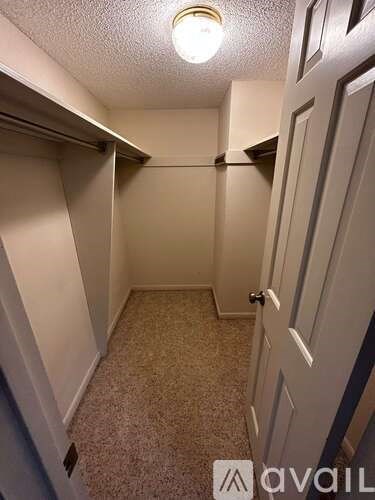 A small, empty room with a carpeted floor and a door on the right.