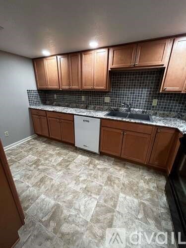 A kitchen with brown cabinets and a white dishwasher.