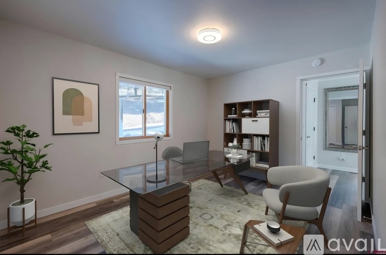A living room with a glass table and a bookshelf.