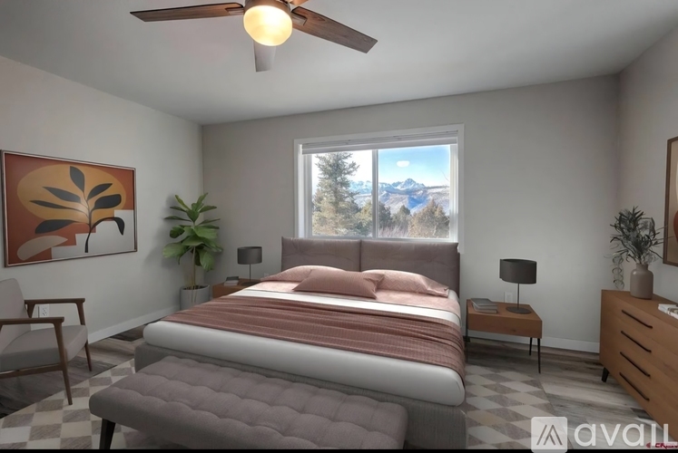 A bedroom with a large bed, a ceiling fan, and a window with a view of the mountains.