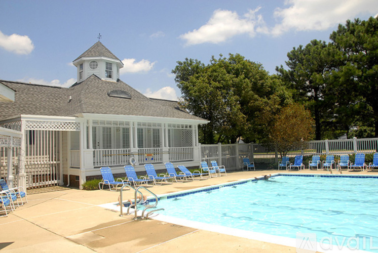A pool with blue chairs and a white building with a clock tower in the background.