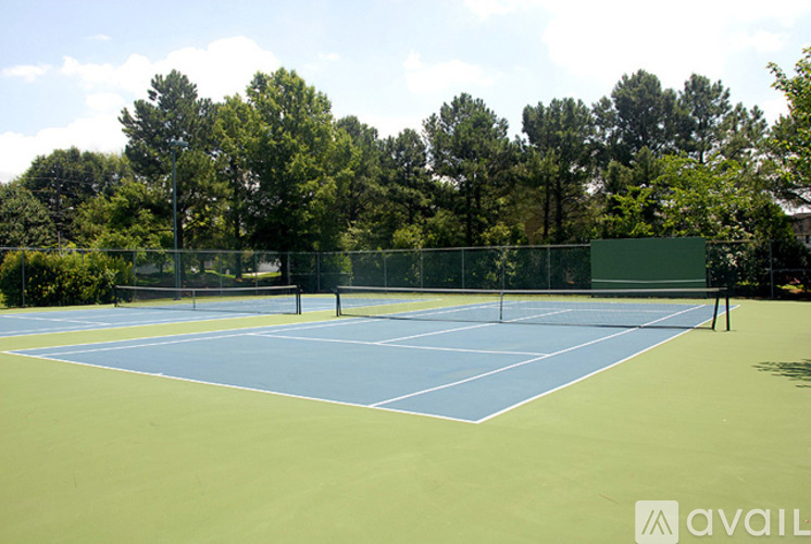 A tennis court surrounded by a fence and trees.