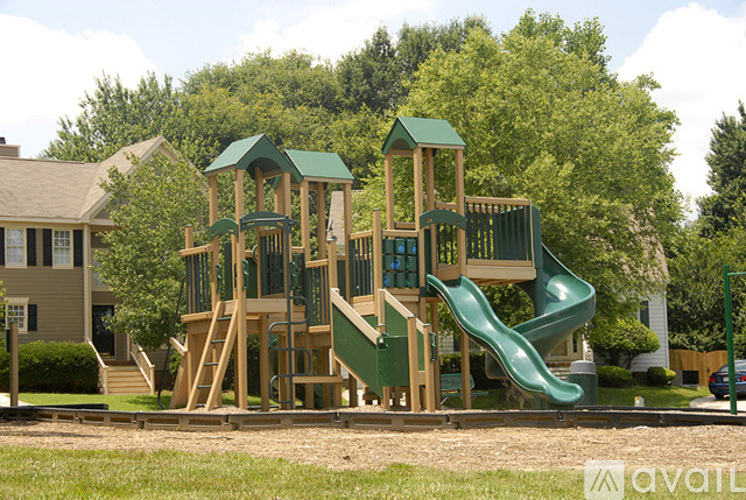 A wooden playground with a green slide and a green roofed structure.