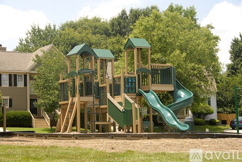 A wooden playground with a green slide and a green roofed structure.