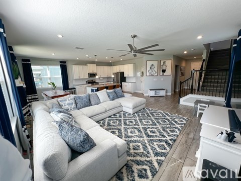 A spacious living room with a white couch and a rug.