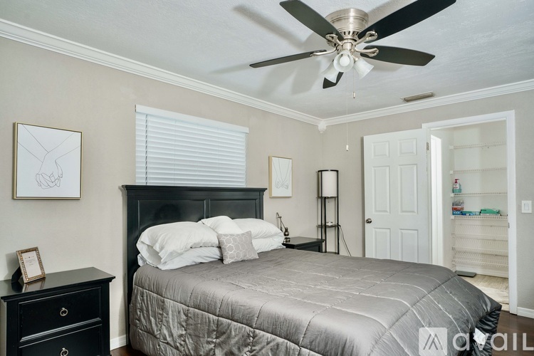 A bedroom with a bed, dresser, and a ceiling fan.