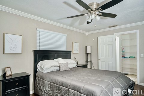 A bedroom with a bed, dresser, and a ceiling fan.