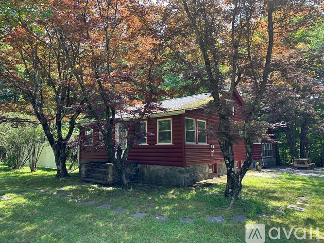 A red house surrounded by trees with autumn leaves.